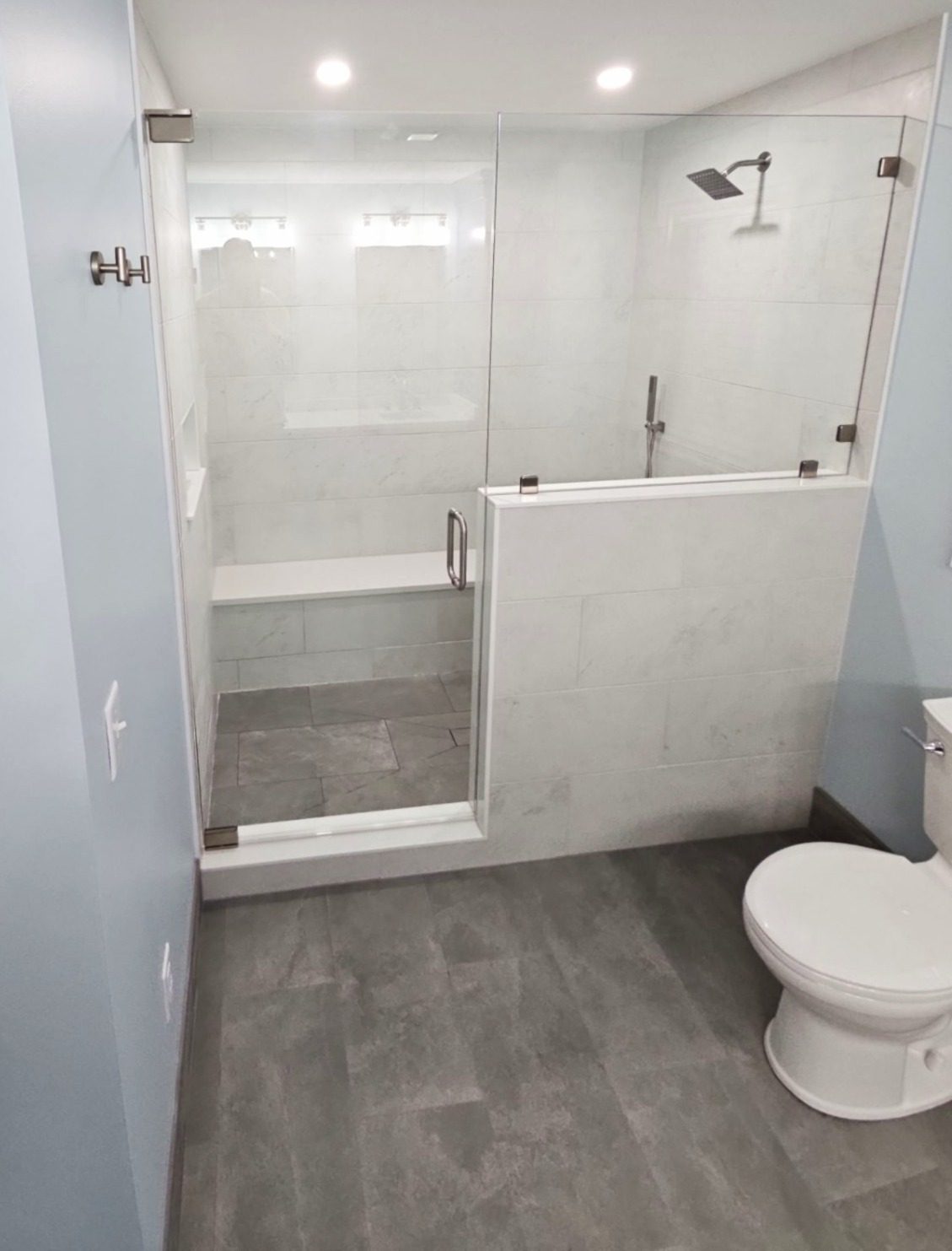 Bedford — frameless glass-enclosed accessible shower with marble-look tile and bench