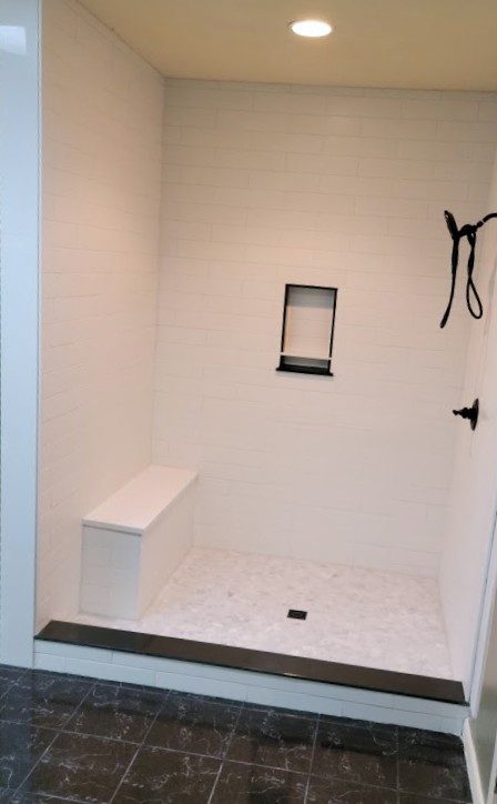Bennington — walk-in shower with subway tile, built-in bench, hexagon mosaic floor, and matte black accents