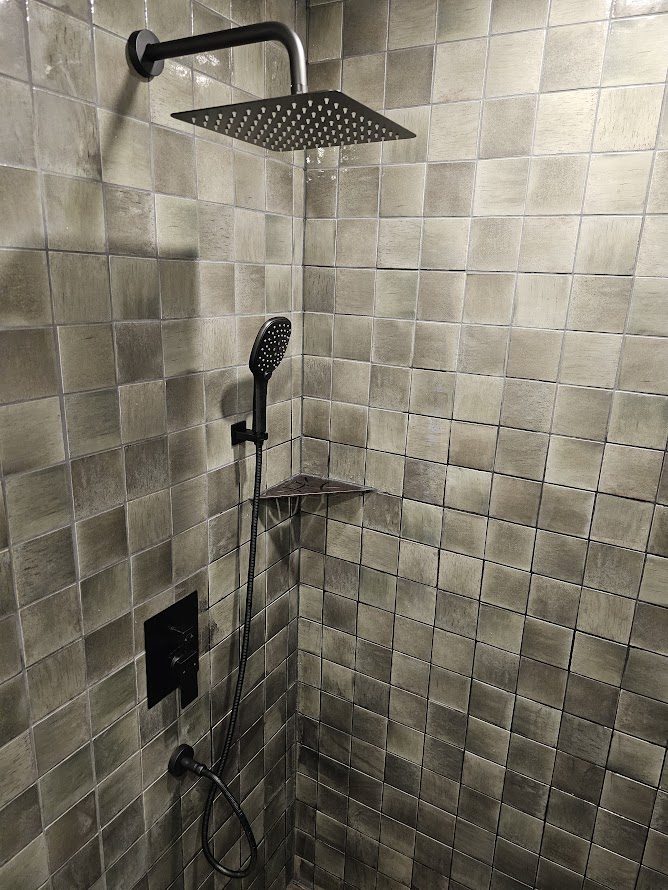 Osceola Mill — walk-in shower with handmade metallic tile and dual rain head in historic cabin