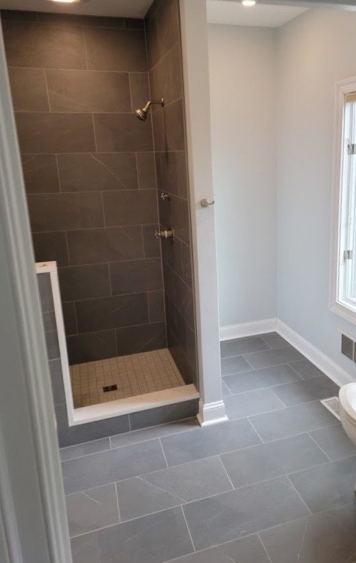 Newport — curbed walk-in shower with slate-look porcelain tile and brushed nickel fixtures