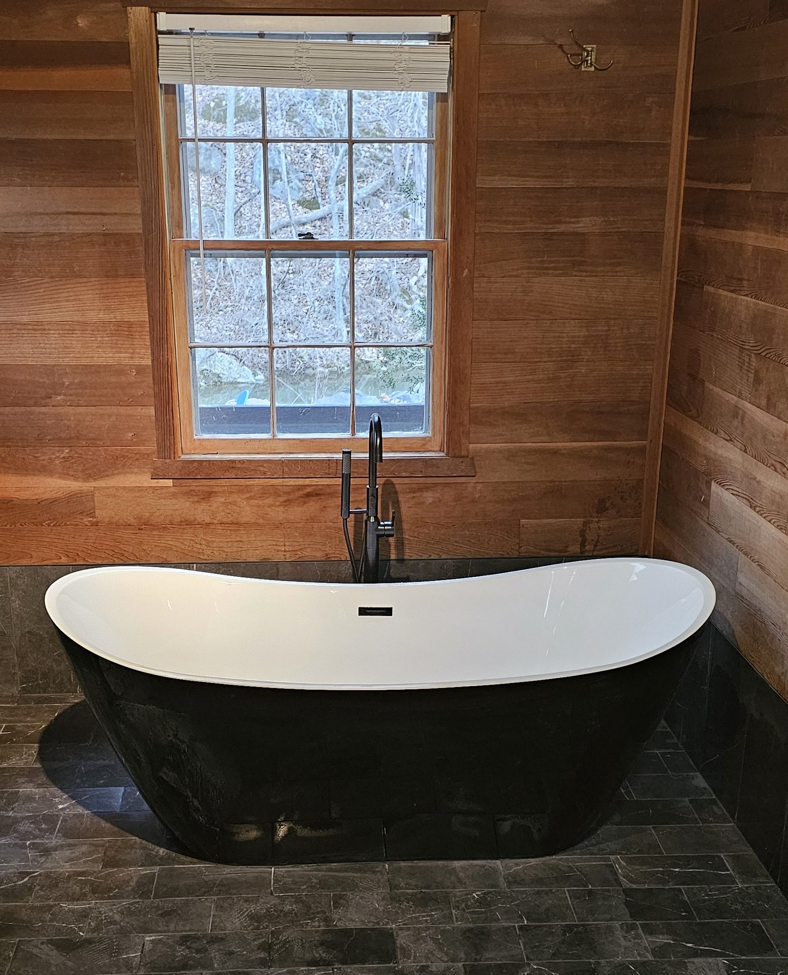Osceola Mill — black freestanding tub centerpiece with matte black floor-mount filler and slate flooring