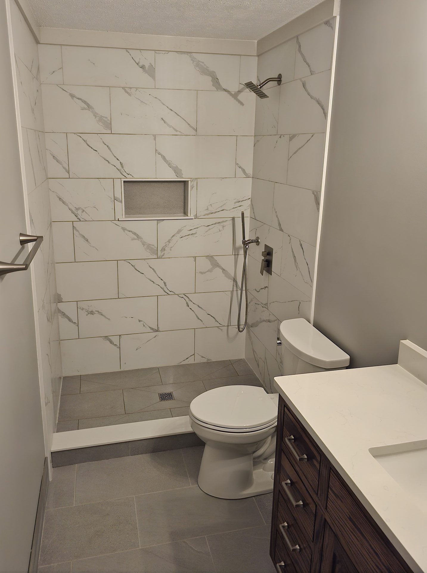 Rutledge — walk-in shower with large-format marble-look tile, built-in niche, and dark wood vanity