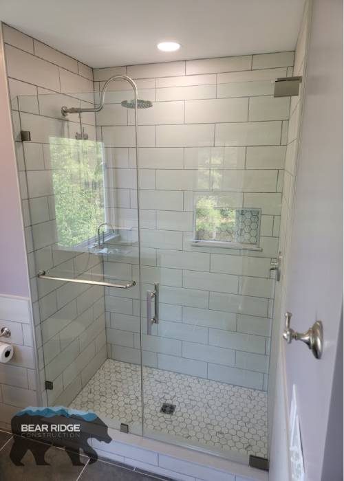 Village — walk-in shower with frameless glass, white subway tile, and hexagon mosaic floor