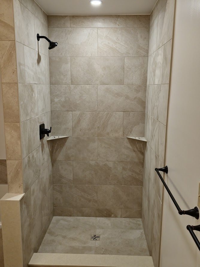 Laurel Springs — walk-in tiled shower with natural stone tile and oil-rubbed bronze fixtures